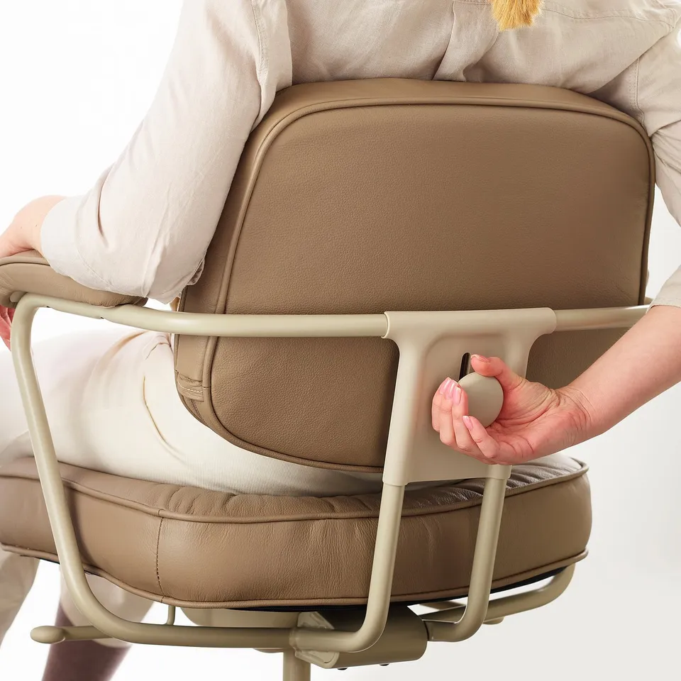 Person adjusting lumbar support on a brown office chair.