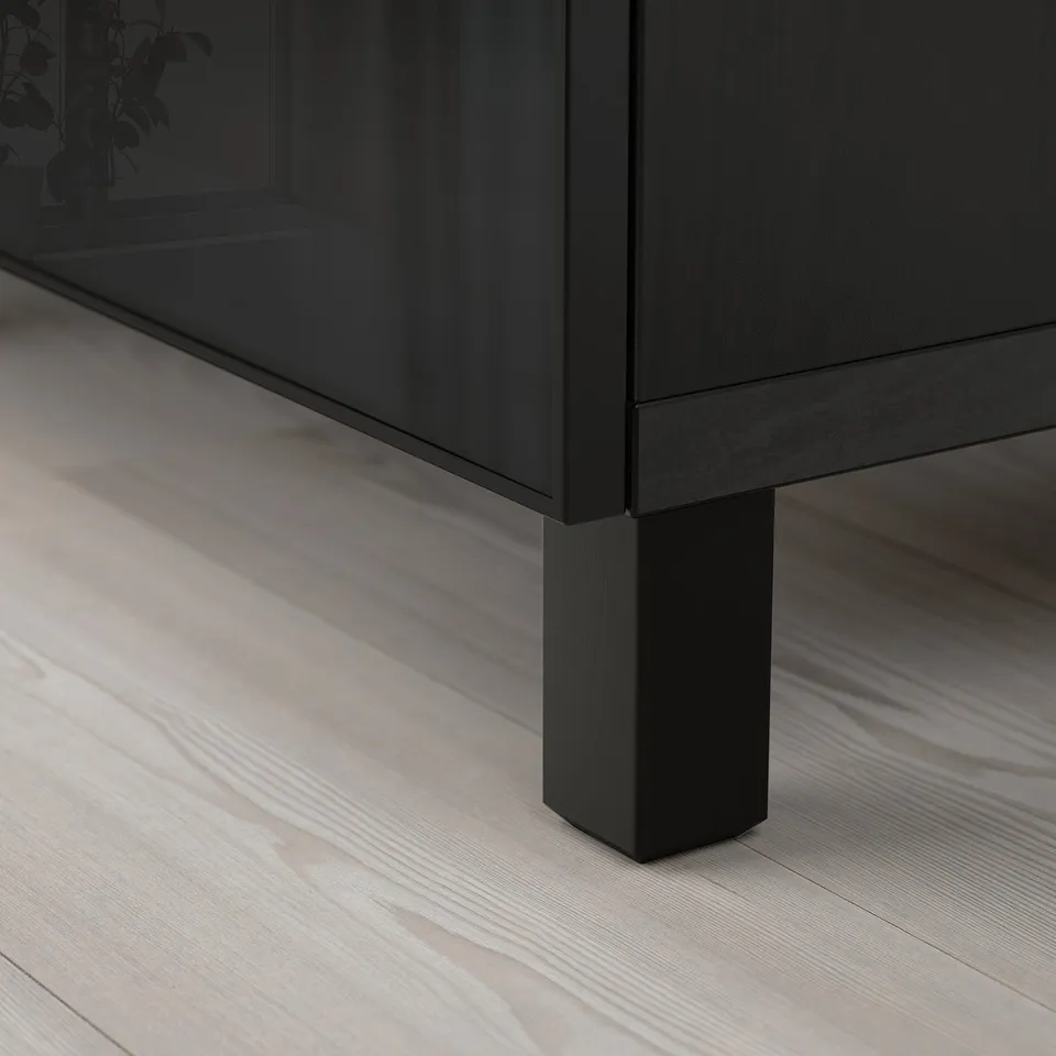 Modern black sideboard on light wood floor, showcasing sleek design and sturdy legs.