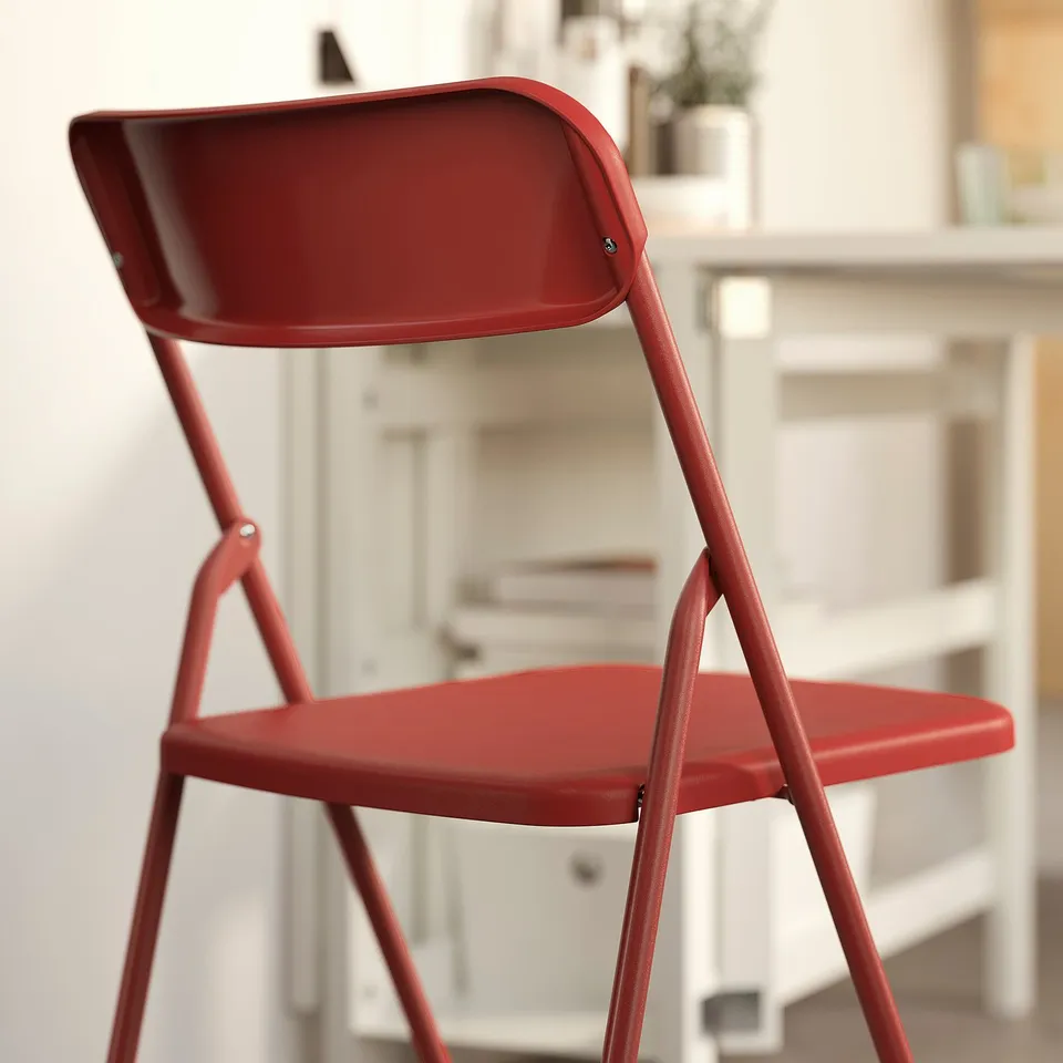 Red folding chair, pre-assembled, sturdy metal frame, saves space when folded.