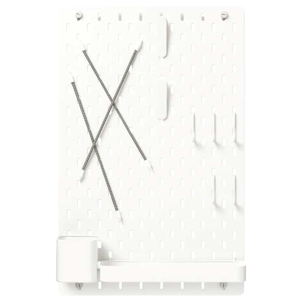 White SKÅDIS pegboard with grey clips and hooks, organised in an x pattern.