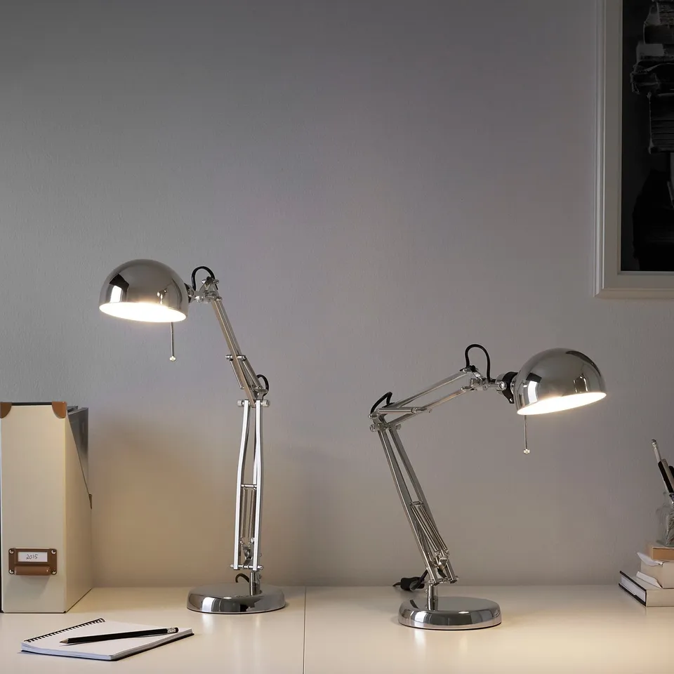 Two silver desk lamps with adjustable arms on a desk.