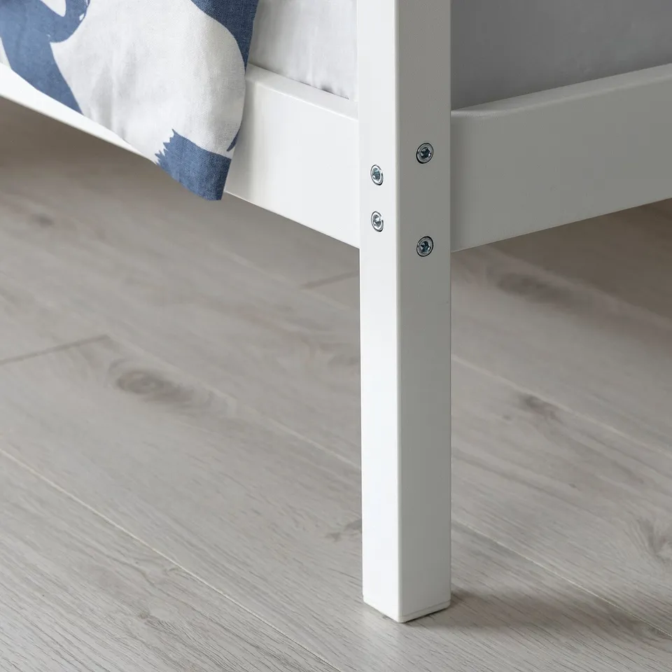 Close-up of sturdy white metal bed leg with horizontal support, showing robust design and clean finish.