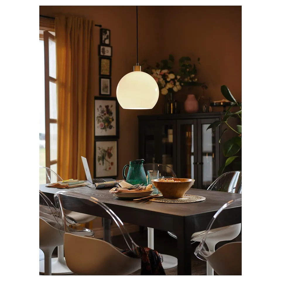 A dining room with a wooden table, white swivel chairs, a pendant light, and decorative items.