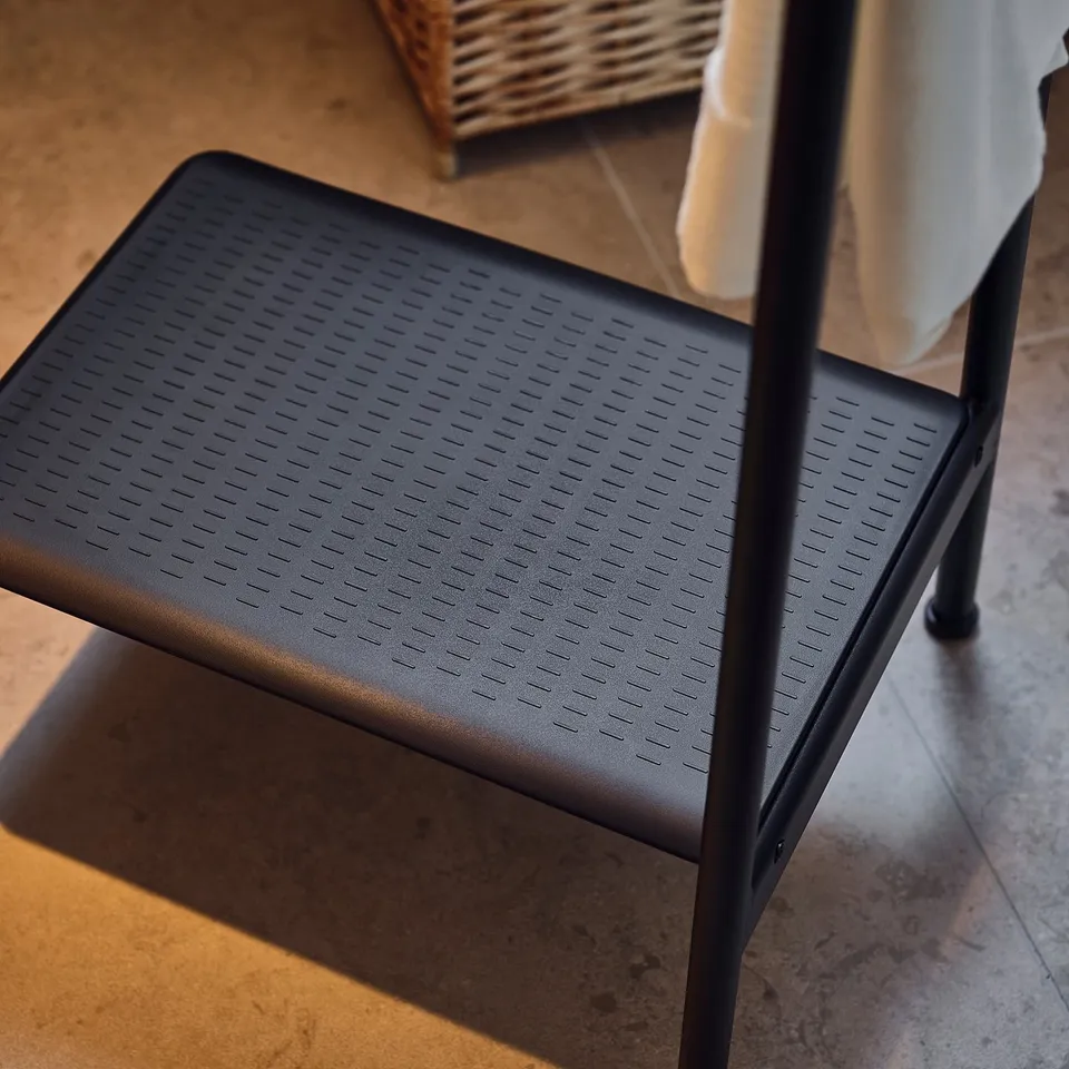 Black plastic step stool with side rail; non-slip; grey floor.