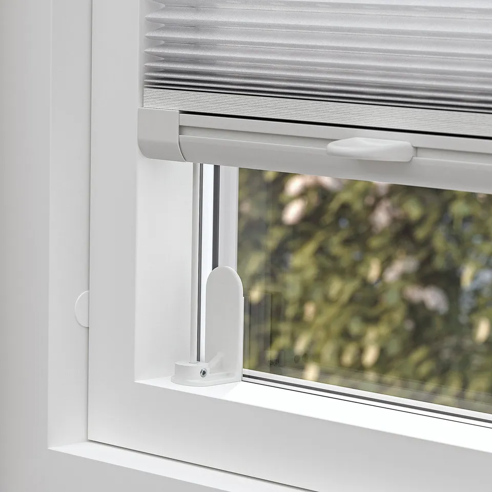 A pleated blind mounted on a window. The blind cordless handles for adjusting light and privacy.