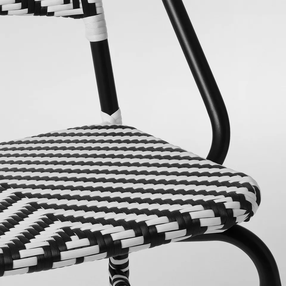 Modern bistro chair with intricately woven black and white pattern, sleek black metal frames, designed for comfort and durability.