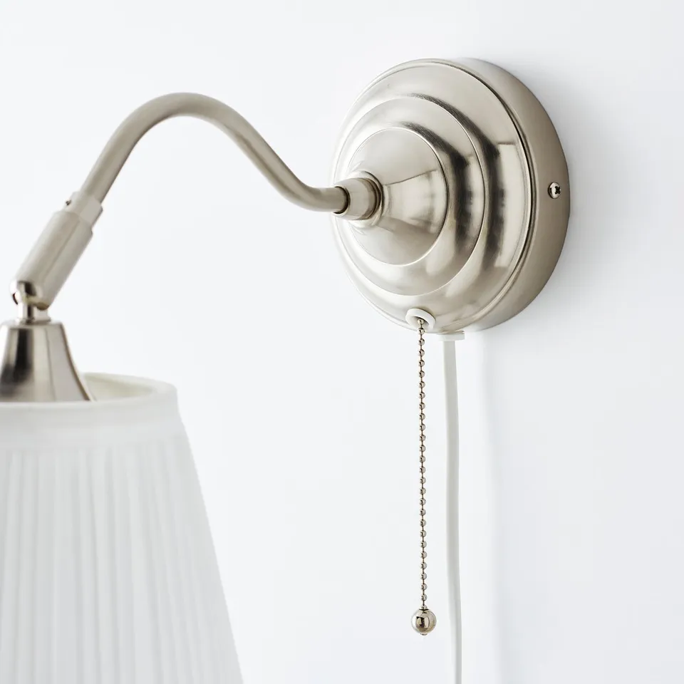 Wall-mounted lamp with adjustable arm, rippled white shade, hanging cord switch, brushed nickel finish.