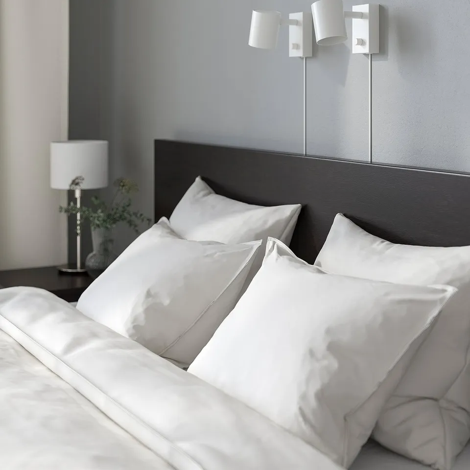 Modern bedroom with MALM bed, white silk pillows, black headboard, and wall lights.