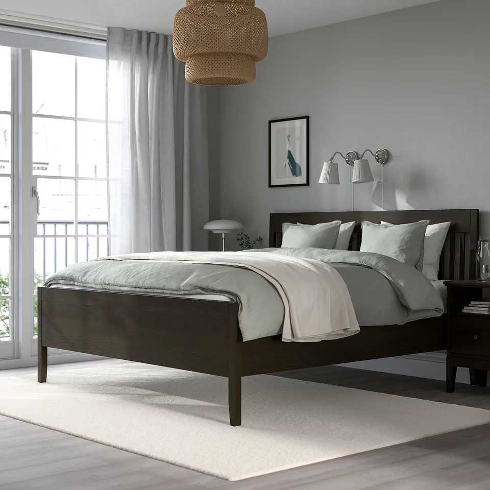 Modern bedroom with queen bed, dark wood frame, grey linens, lamps, large window, city view.