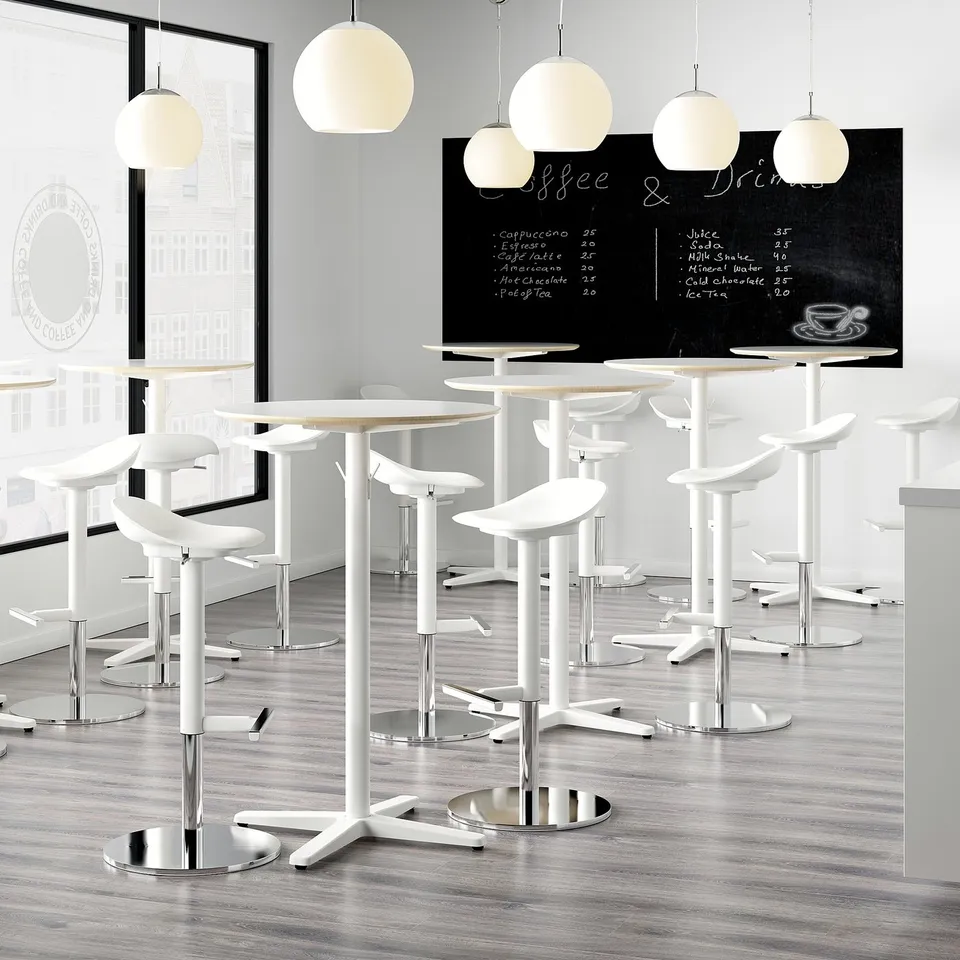 Modern cafe with white bar stools. Each stool a scooped seat and chrome base, adjustable with one hand for comfort.