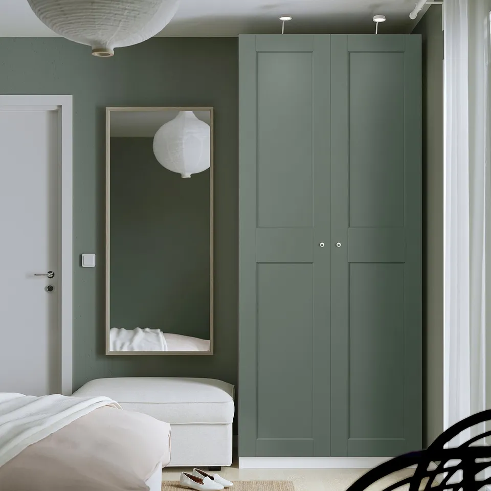 Modern bedroom with tall teal green PAX wardrobe. White bed & mirror beside it.