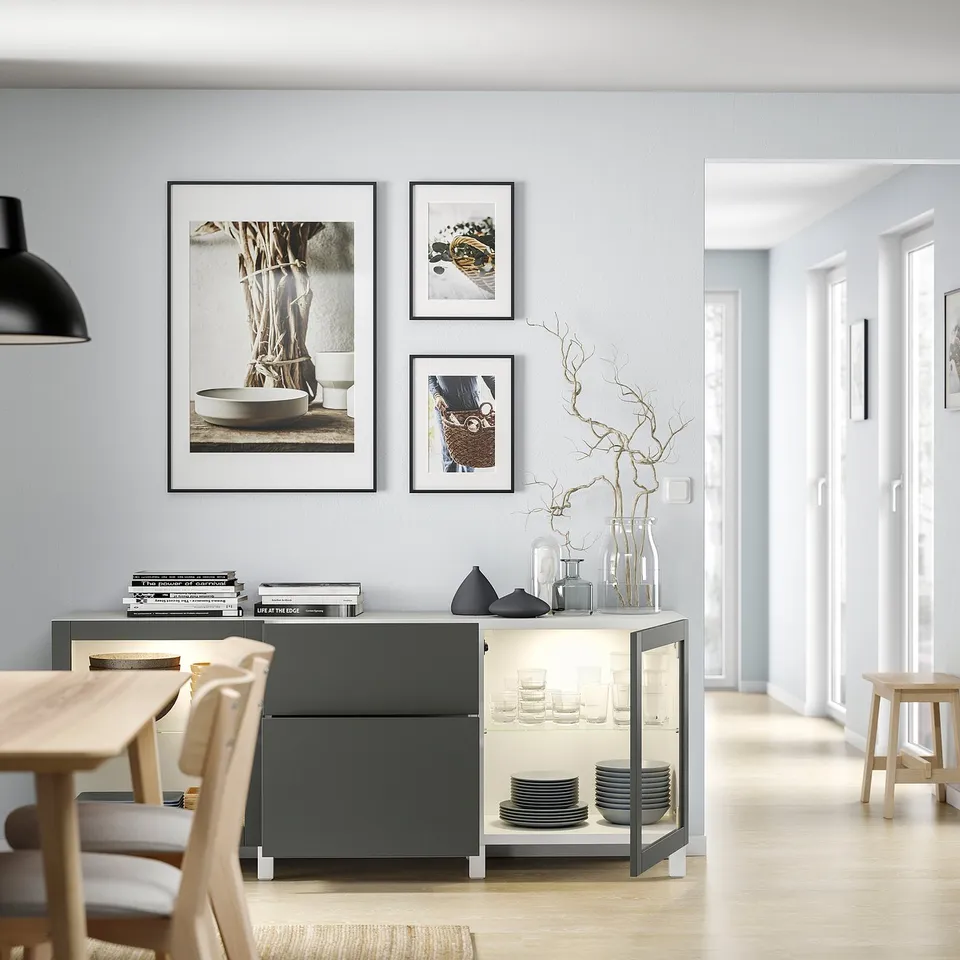 Modern dining room with wood floors, grey buffet, art, and books.