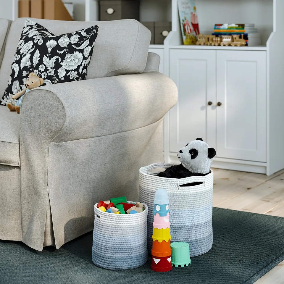 Grey basket with toys near armchair.