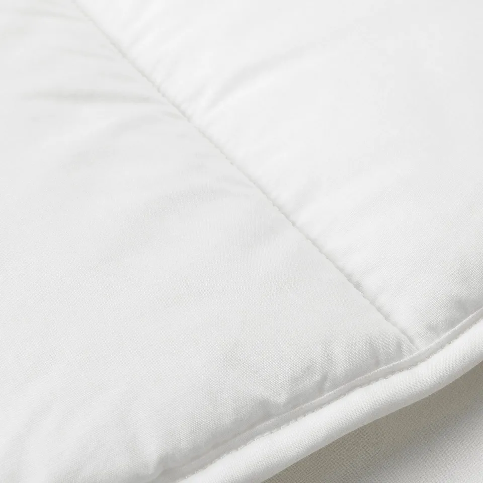 Close-up of a high-quality, soft, white duvet with smooth fabric and precise stitching.