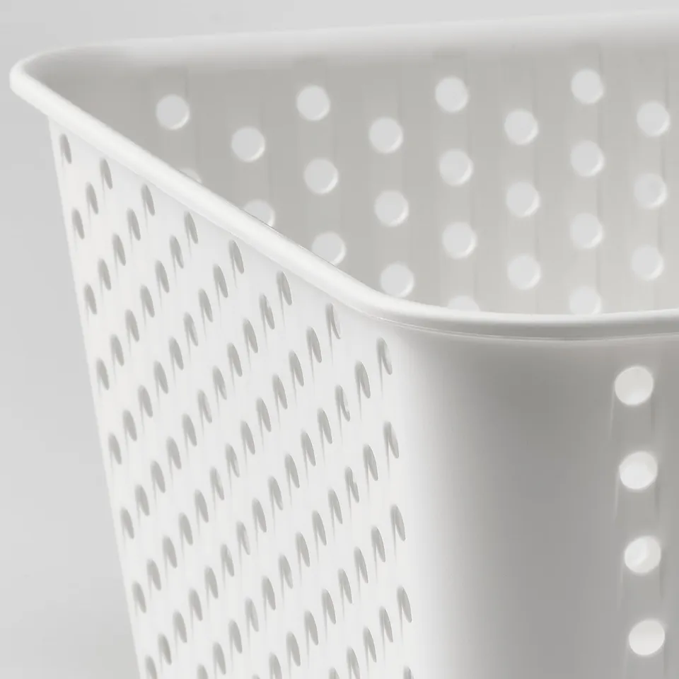 Close-up of white plastic storage basket with evenly spaced holes for drainage and ventilation.