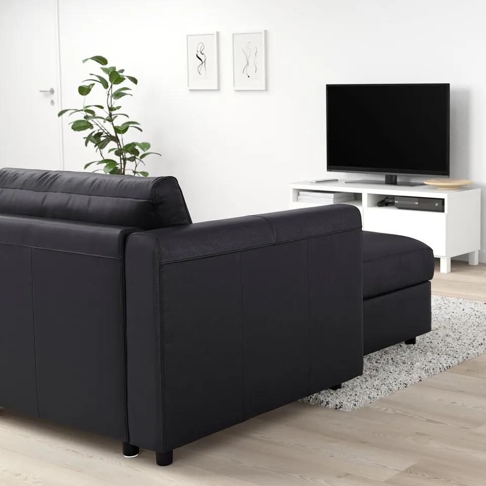 Modern living room with black VIMLE sofa, white tv stand, and plants.