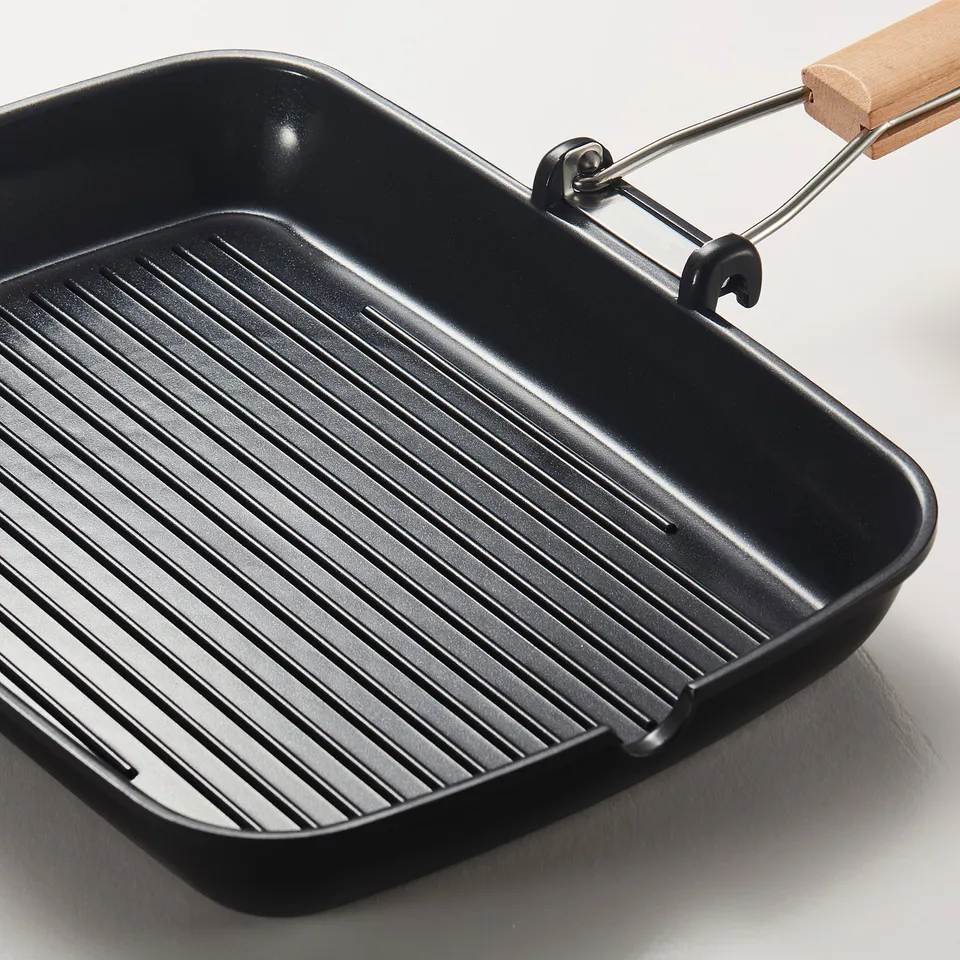 Grill pan with wooden handle and deep ridges for even cooking and easy cleanup.