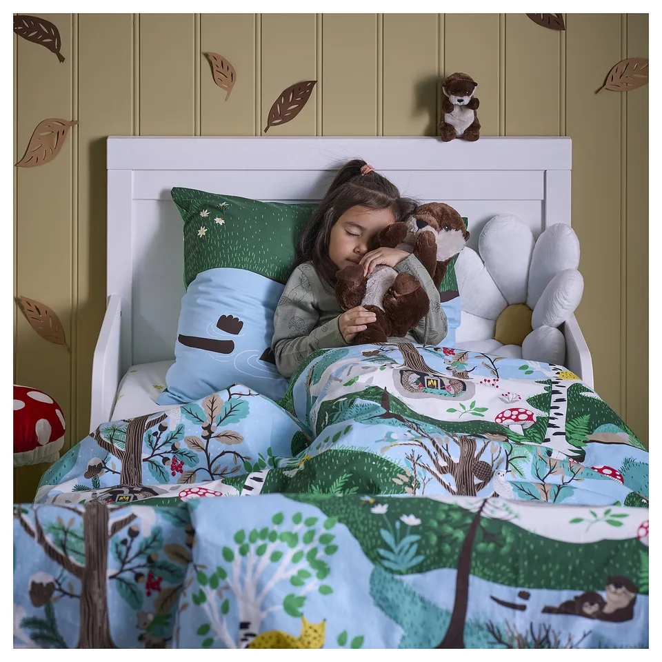 Child sleeps in SKOGSDUVA woodland bed with stuffed toy.