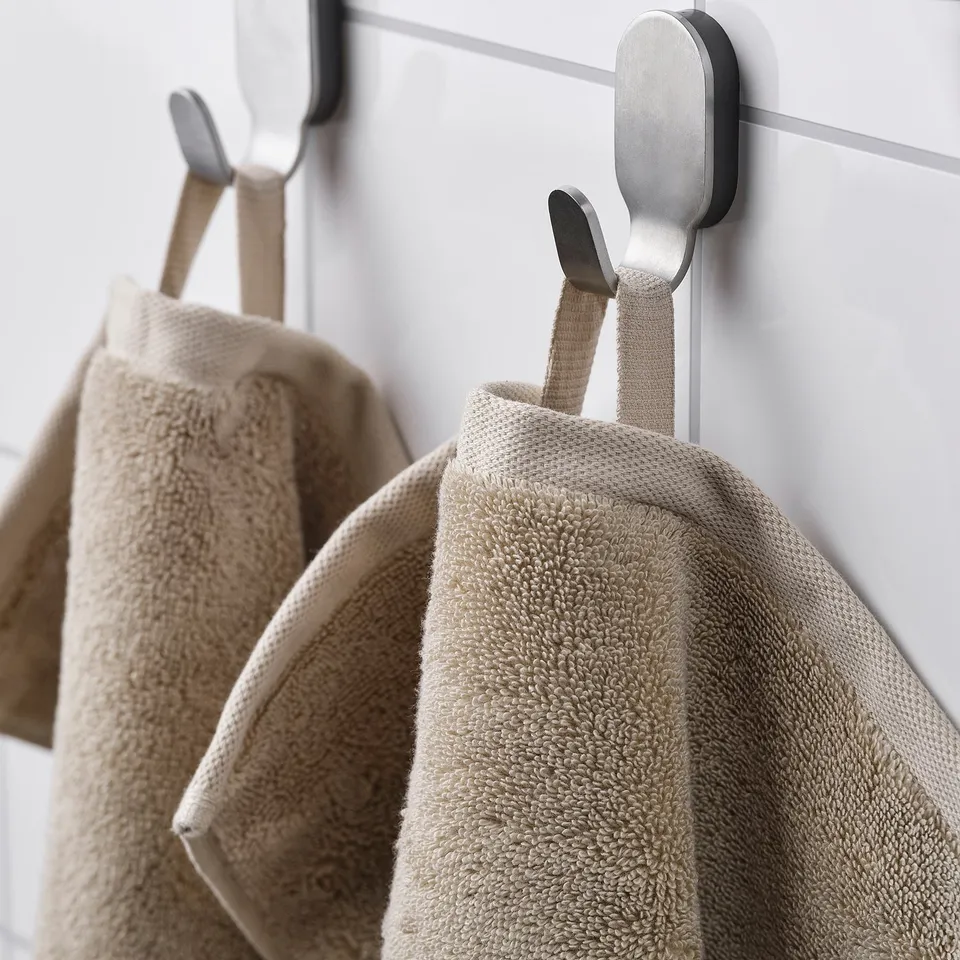Two beige towels hang neatly on metallic hooks, showcasing their soft texture and organised storage.
