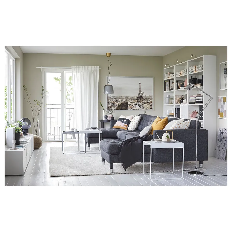 Modern living room with grey LANDSKRONA sofa, white shelving, glass coffee table, and green curtains. Large paris photo on wall.