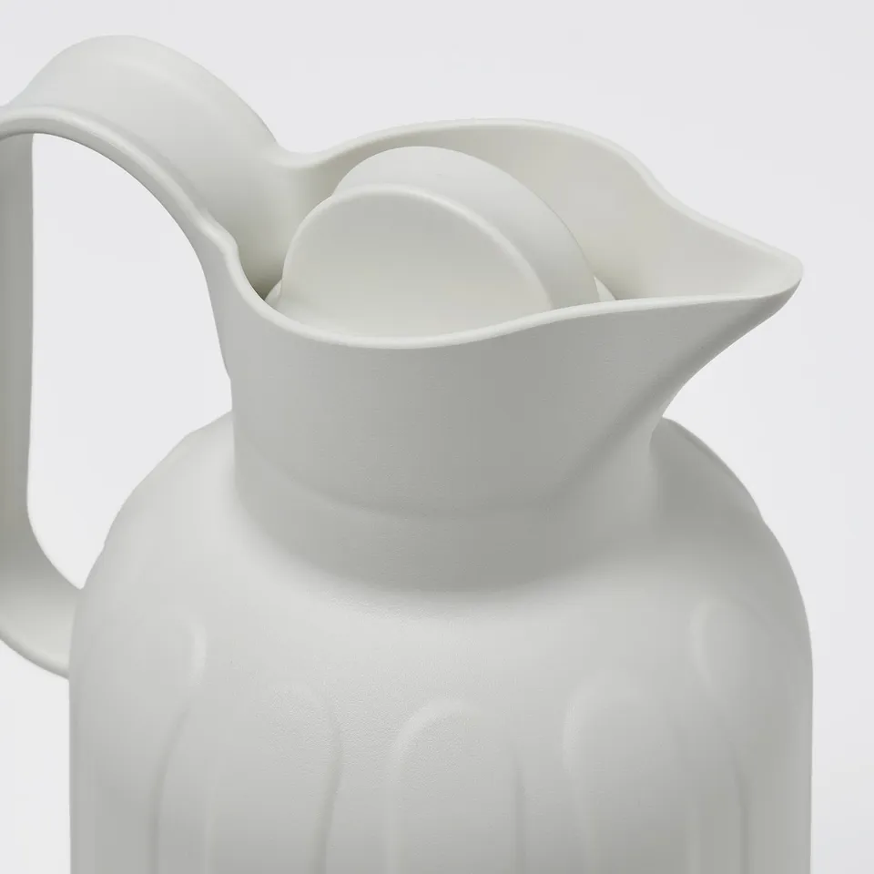 A sleek white vacuum flask with vertical ridges, secure side handle, and stylish curve.