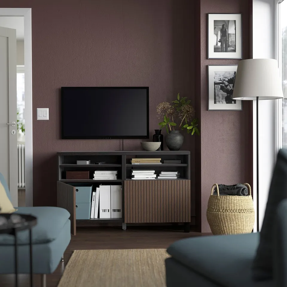 Modern living room with BESTÅ tv bench, flat-screen tv, framed pictures, and blue chairs.