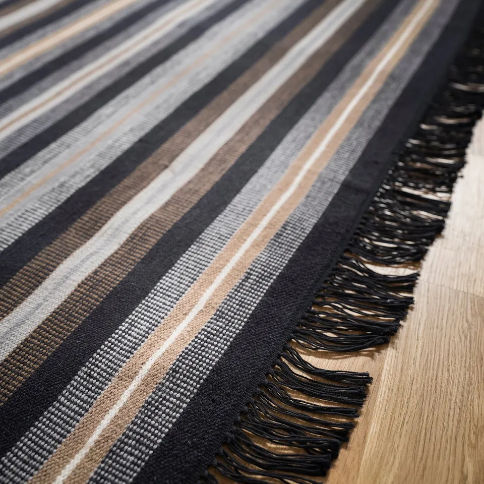Close-up of a handwoven rug featuring bold striped patterns in earthy tones, showcasing high-quality wool and cotton craftsmanship.