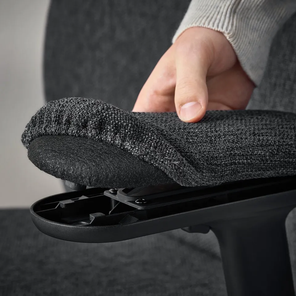 Adjustable armrest on ergonomic office chair. Hand shown moving armrest for comfort.