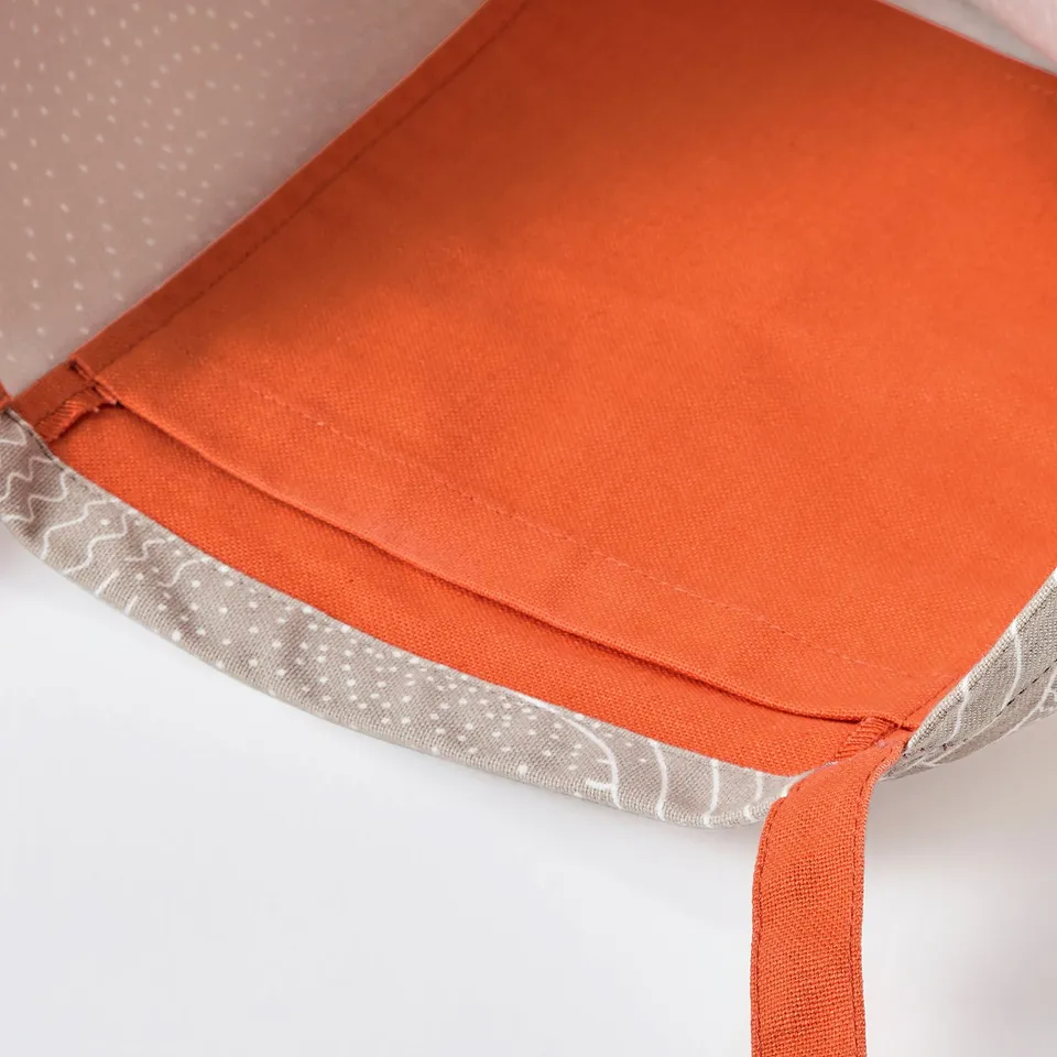 A close-up of an orange fabric item with neat stitching and patterned edges.