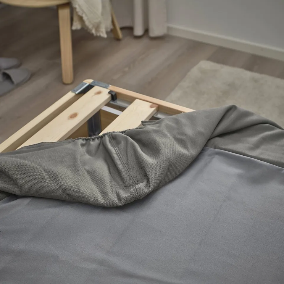 Bed base with removable, washable cover shown partially assembled on floor.
