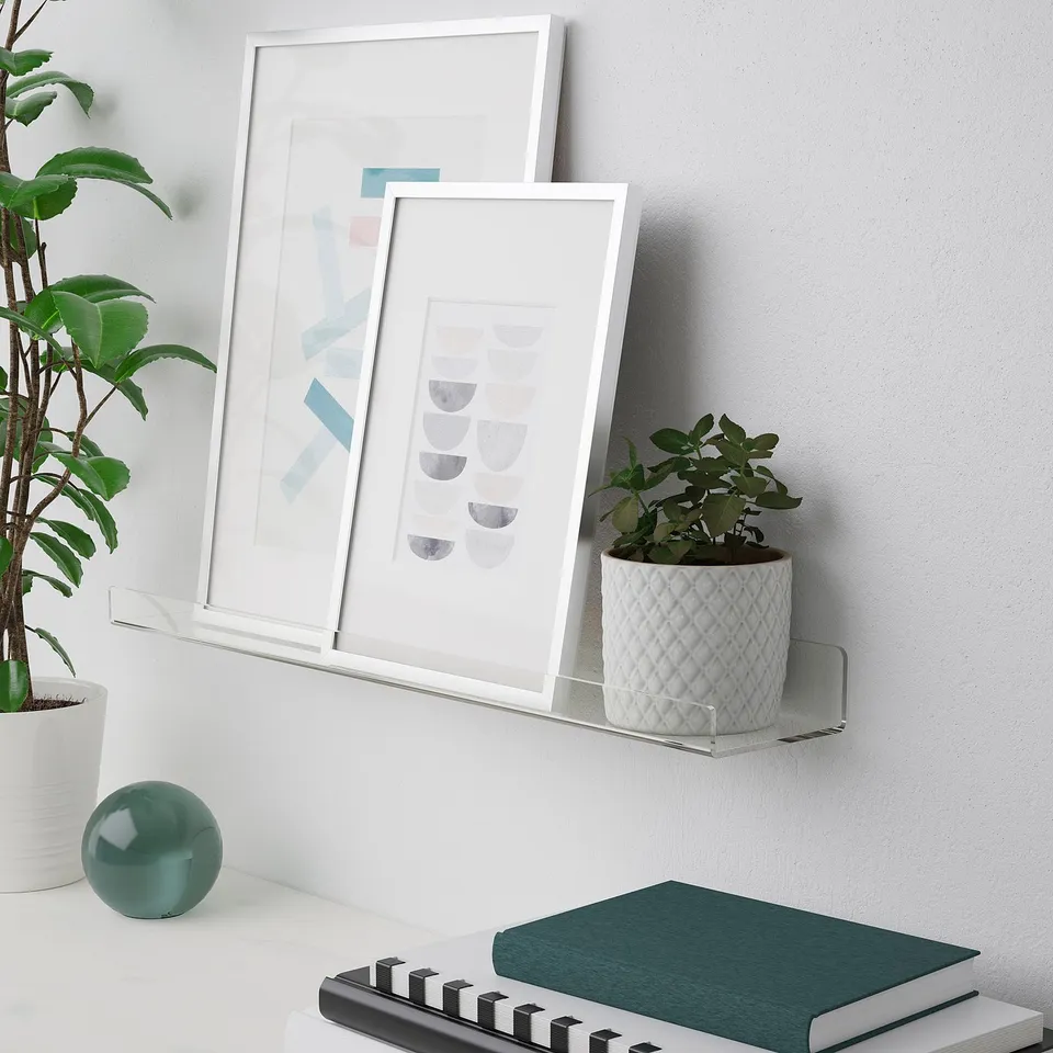 A shelf displays framed art and a white plant.