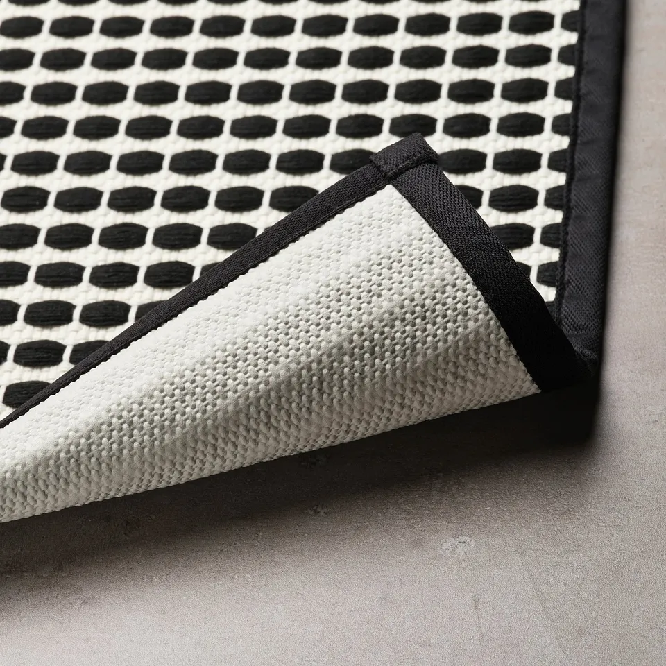 Black and white patterned bath mat with textured surface and latex backing, designed to stay in place on smooth, clean surfaces.