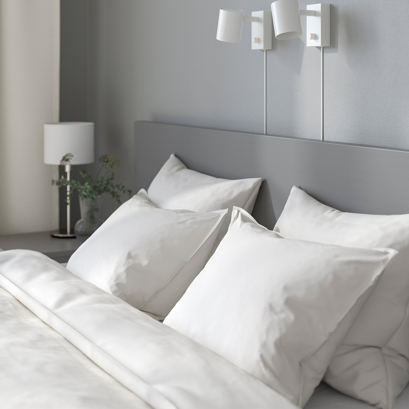 Neatly-made bed with white pillows, grey headboard, wall lights, and bedside lamp with greenery.