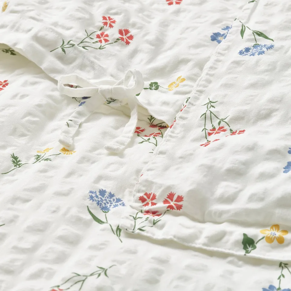 Elegant white duvet with floral patterns and seersucker texture for breathability, secured by ties.