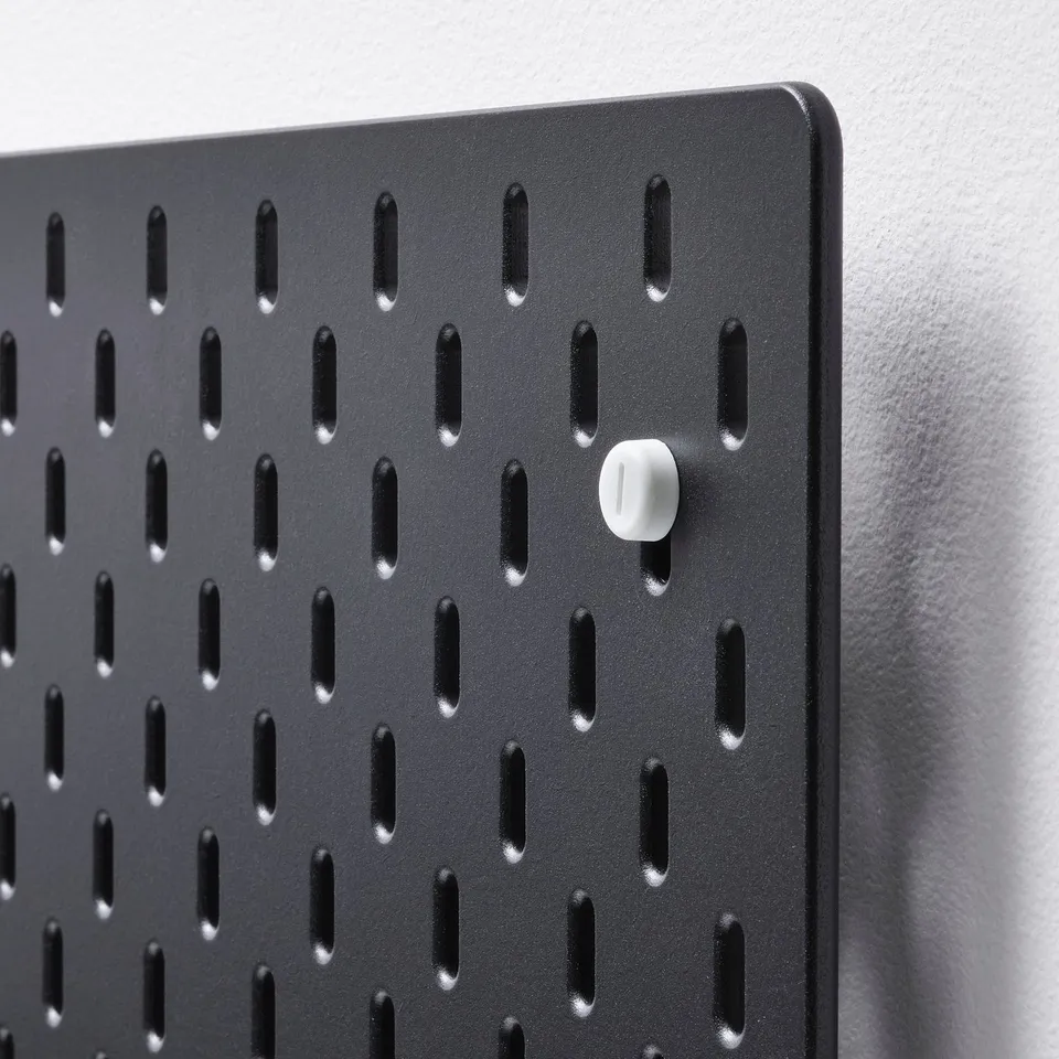 Black pegboard with evenly spaced holes, mounted on a white wall, showcasing high-quality design and material.