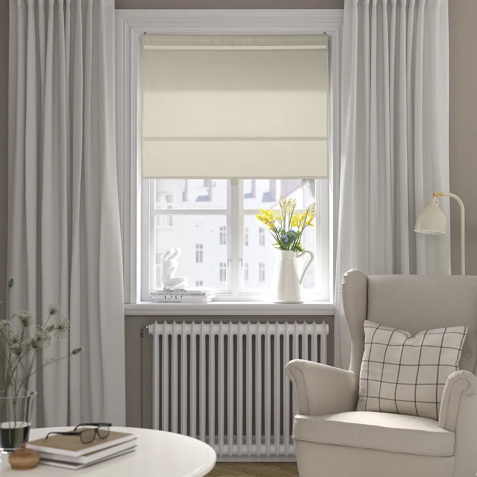 Modern living room with RINGBLOMMA blind, grey armchair, and minimalist decor.