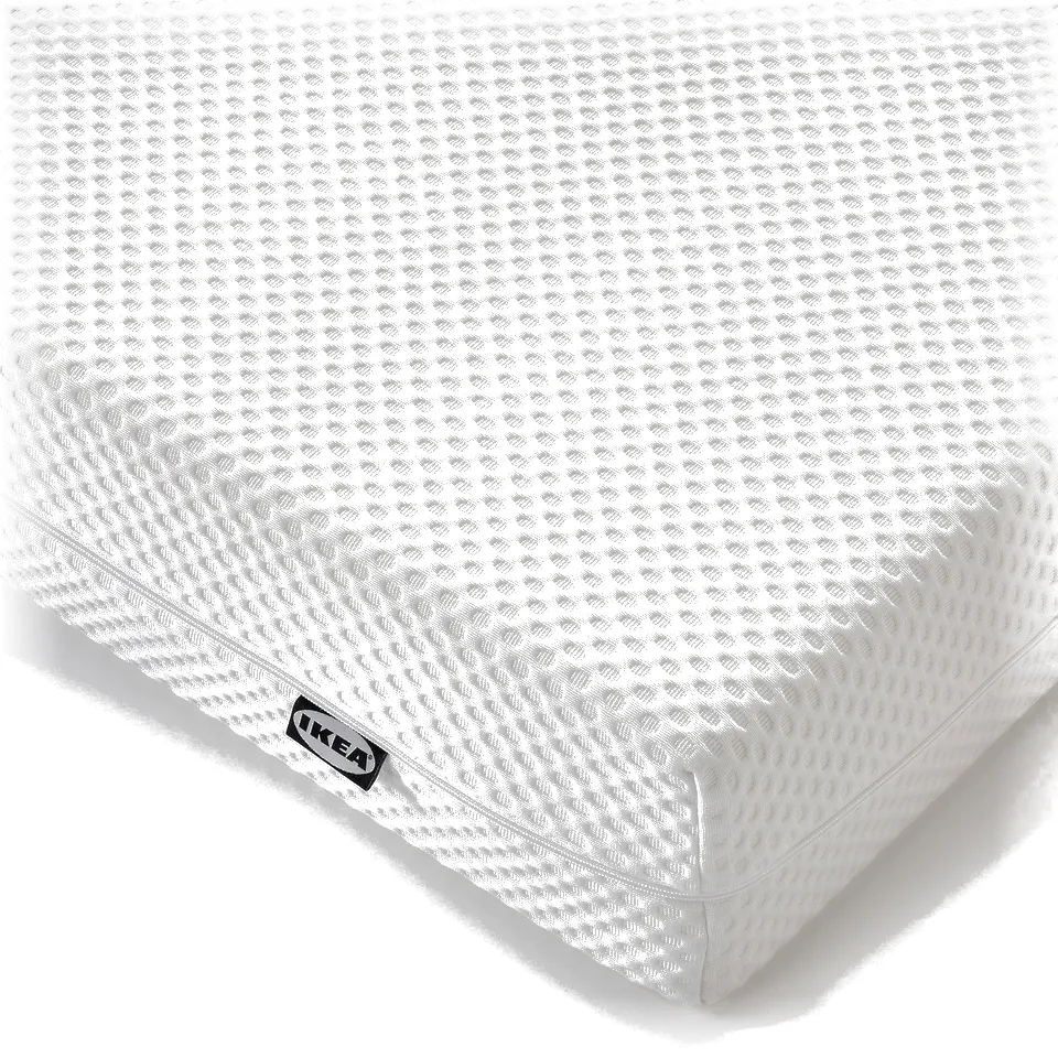 Close-up of a firm, white foam mattress by IKEA. Textured surface, soft removable cover, showcasing quality and comfort.