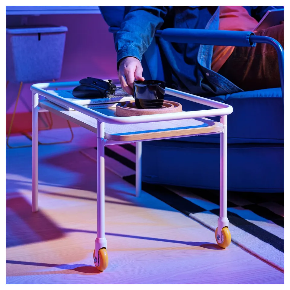 Person reached for a drink on a BRÄNNBOLL side table with wheels.