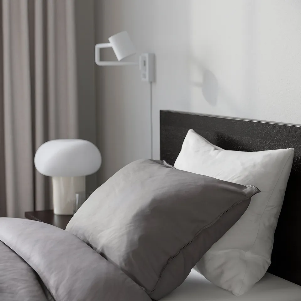 Cosy MALM bed with adjustable sides, modern lamp, and minimalist decor.