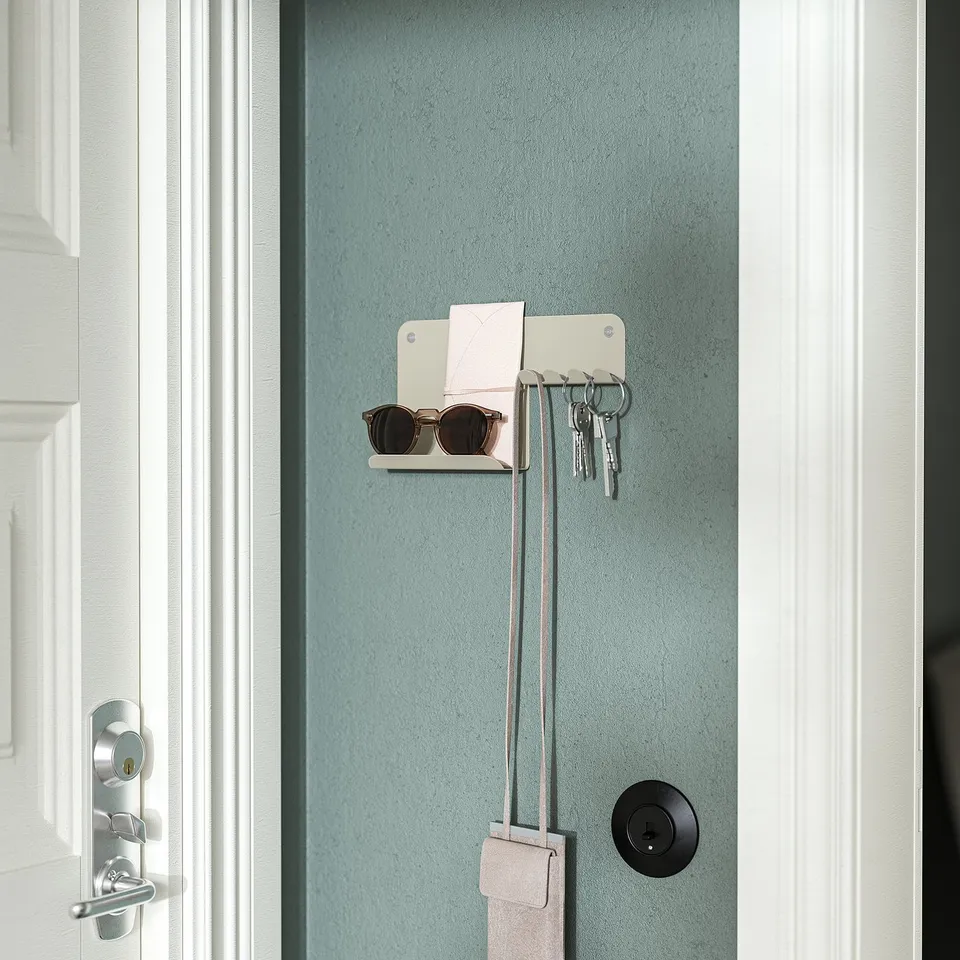 Wall-mounted organiser holds keys, sunglasses, and notes; provides hallway storage.