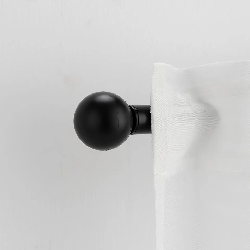 A VÄSENTLIG black finial. It is small, round, and simple, made from recycled plastic. It mounts onto a curtain rod.