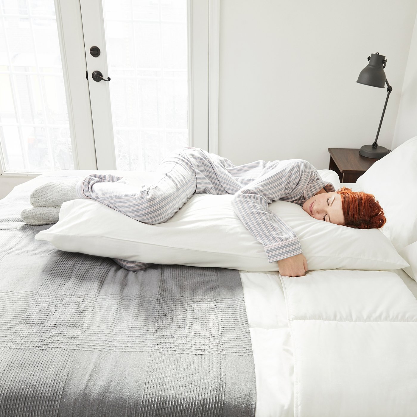 Person sleeps peacefully on soft, breathable cotton pillowcase in cosy, minimalist bedroom.