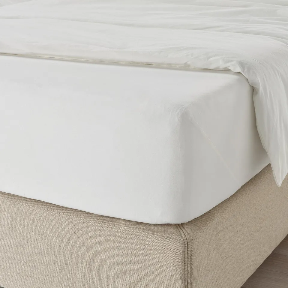 Bed with white DVALA cotton fitted sheet, elastic edges, neatly made.