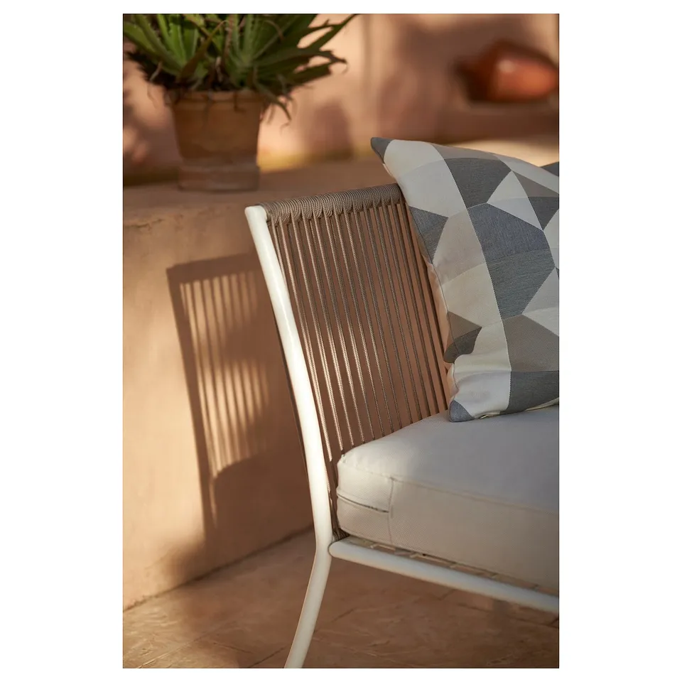 White metal outdoor chair with grey cushion and patterned pillow, ideal for patios.