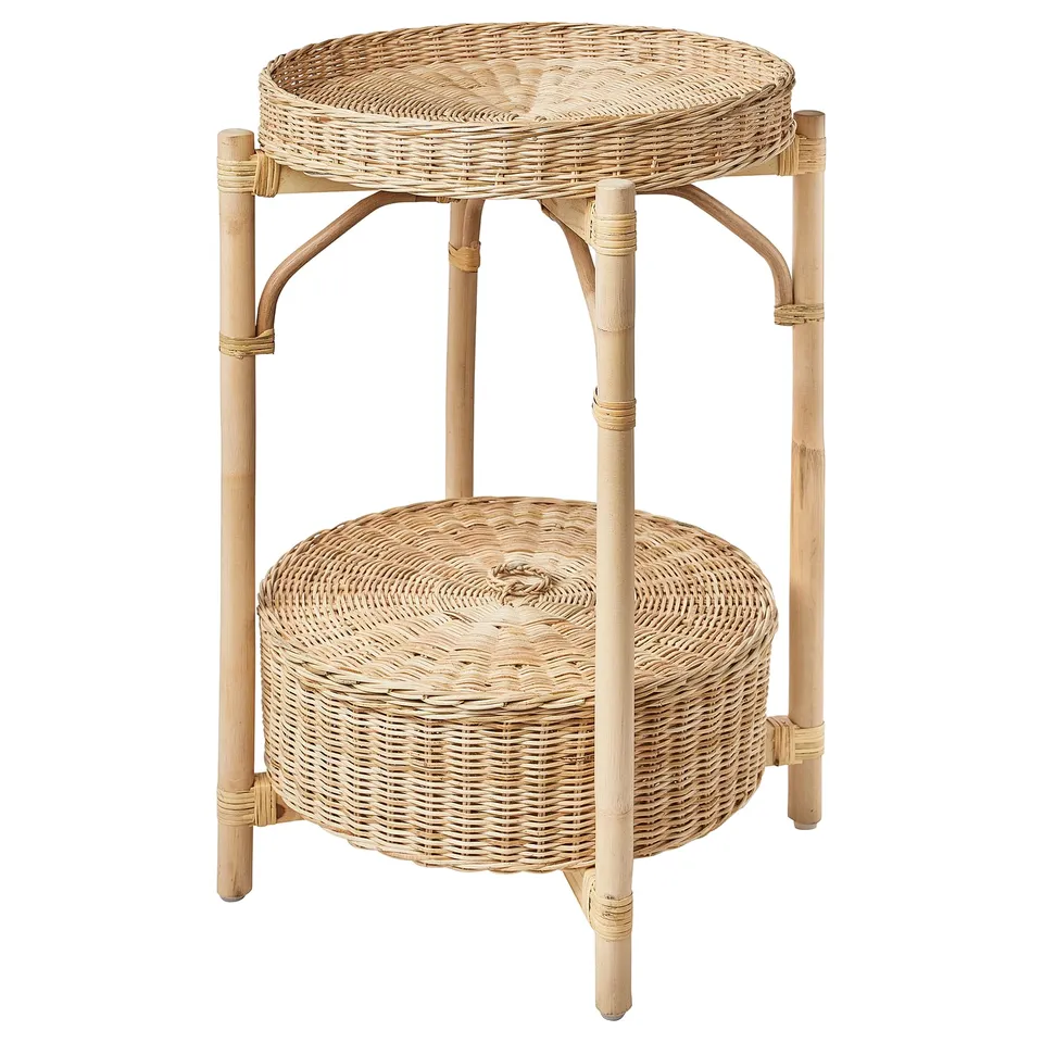 The TOLKNING natural rattan side table with a round wicker tray top and bottom, supported by four bamboo legs with crossbars.