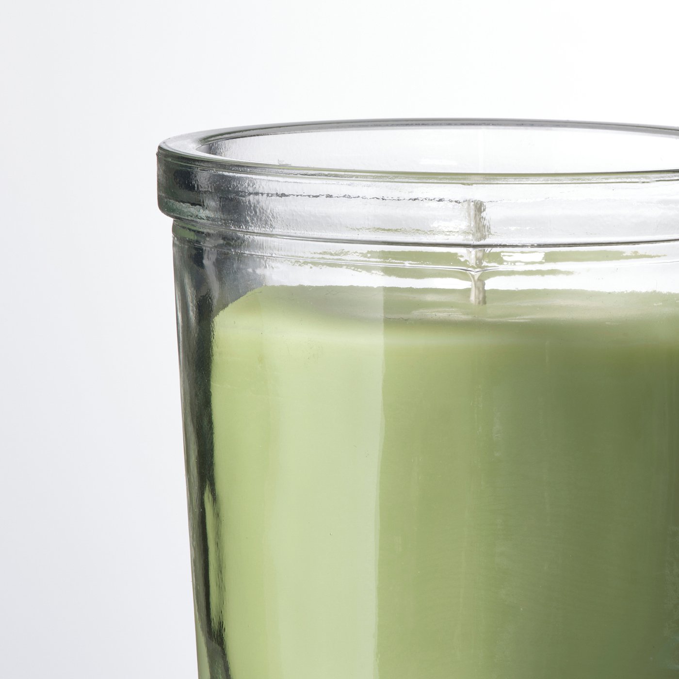 Clear, green-tinted glass candle with smooth, even wax surface.