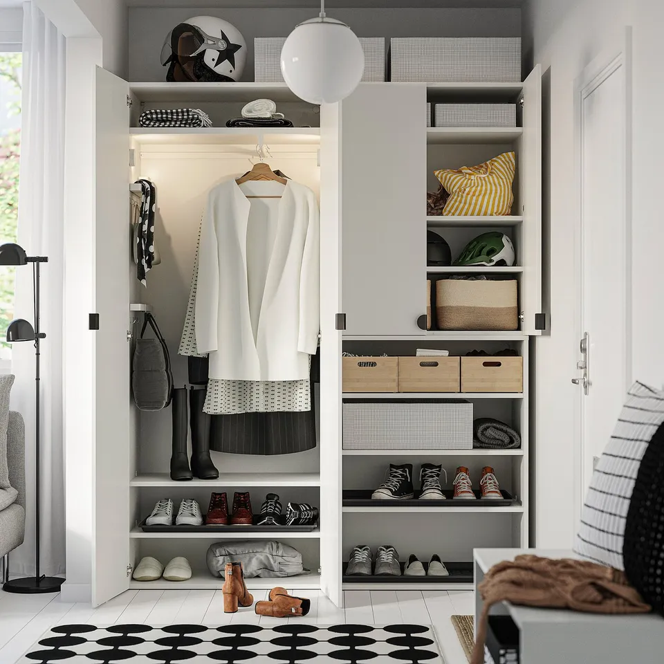 Organised closet with adjustable feet, hanging clothes, shelves for shoes, and storage boxes. Bright lighting and minimalist design.