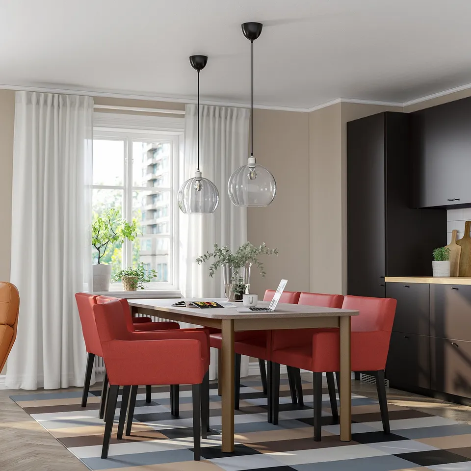 Modern dining room with STRANDTORP table, red chairs, black pendants, large windows, and patterned rug.