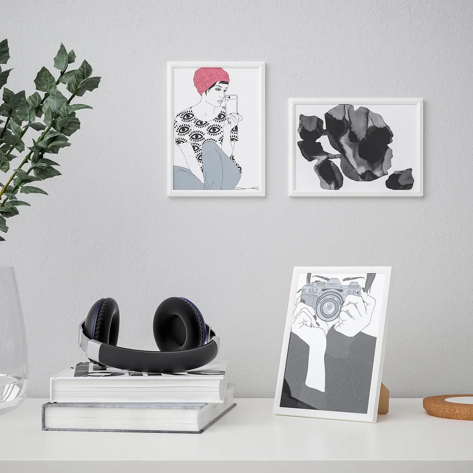 A desk with white books, headphones, and an easel displaying a camera illustration.