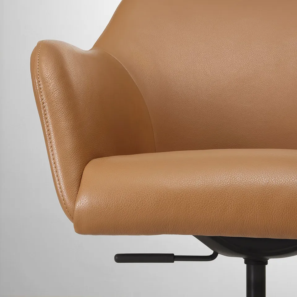 Close-up of a plush, upholstered tan leather chairs cushioned seat and backrest, showcasing its smooth, high-quality texture and comfort.